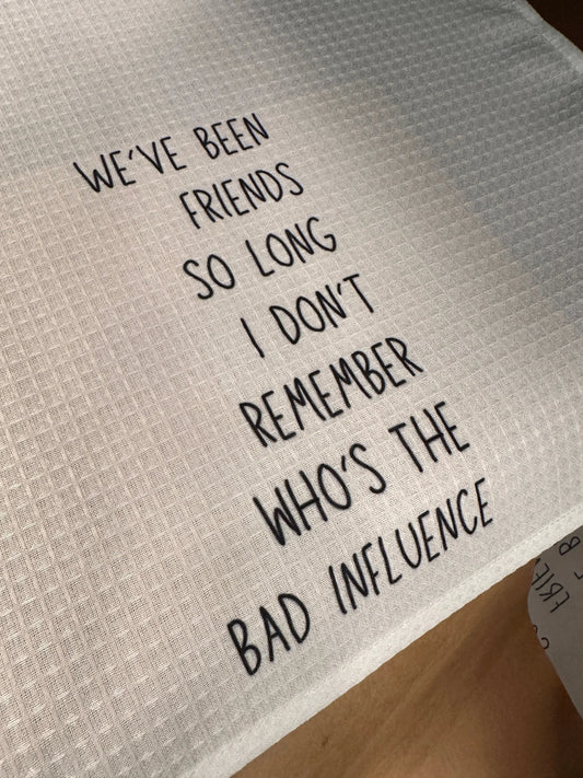 White waffle-weave 18x28 tea towel printed with the phrase “They say it takes a village, but it also takes a vineyard” in black lettering.