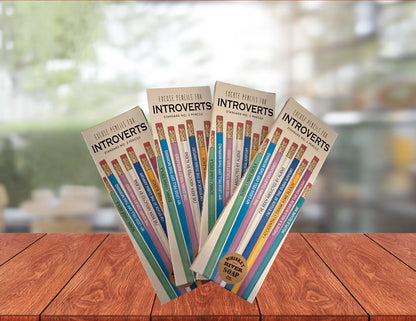 Four packs of “Pencils for Okay Moms” displayed on a wooden table, featuring pink No. 2 pencils printed with funny motherhood sayings.