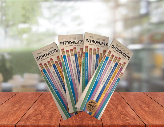 Four packs of “Pencils for Okay Moms” displayed on a wooden table, featuring pink No. 2 pencils printed with funny motherhood sayings.