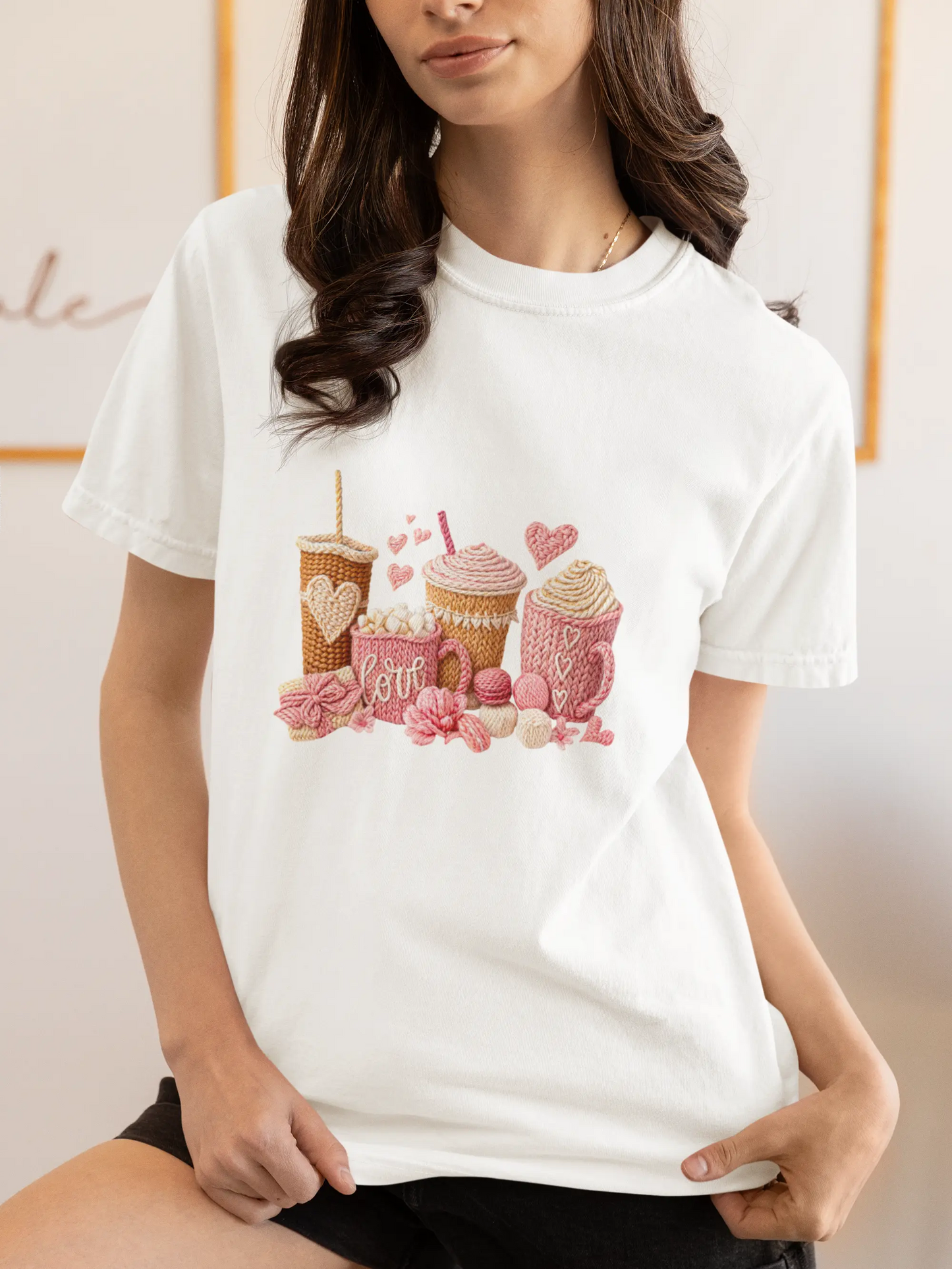 Model wearing a white Valentine’s Day graphic t-shirt featuring pink coffee and cocoa drinks with heart details