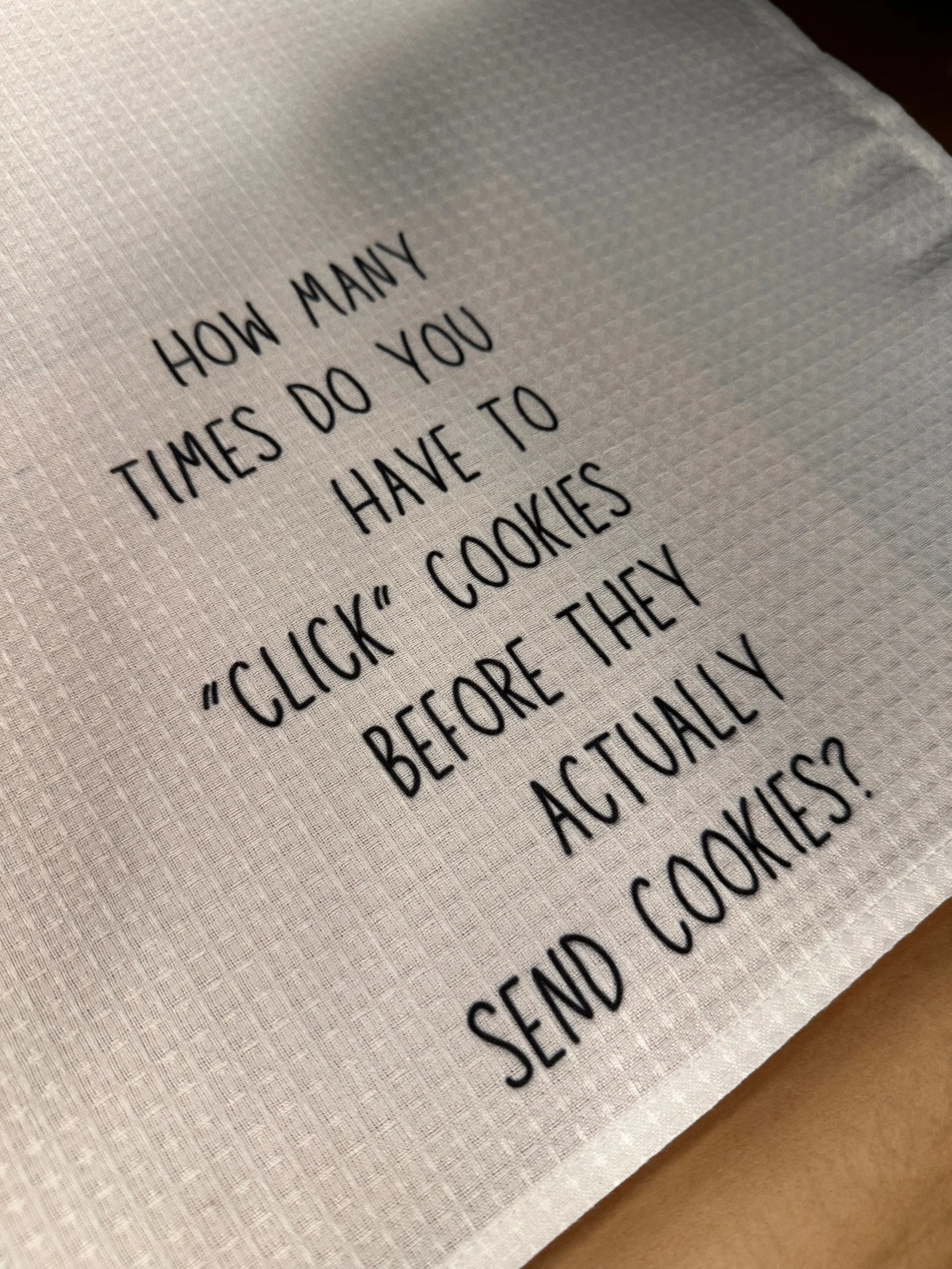 White 18x28 polyester waffle-weave tea towel printed with the text “How many times do you have to click cookies before they actually send cookies?” in black lettering.
